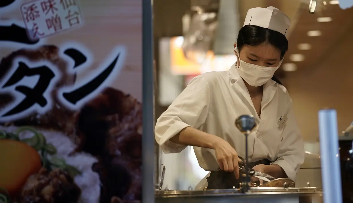 Seorang pegawai restoran yang memakai masker untuk membantu mencegah penyebaran virus corona menyiapkan hidangan untuk pelanggan di Tokyo, Kamis (10/9/2020). Ibukota Jepang mengonfirmasi lebih dari 270 kasus virus korona pada hari Kamis. (AP Photo / Eugene Hoshiko)