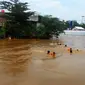 Usai banjir, anak-anak Kampung Pulo sengaja menghanyutkan diri dari jembatan Kampung Melayu hingga Jalan Jatinegara Barat, Jakarta Timur. (Liputan6.com/Ahmad Romadoni)