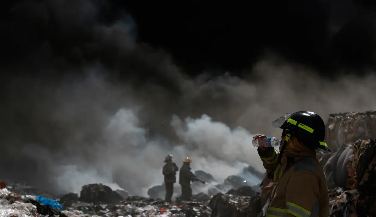 Seorang pemadam kebakaran beristirahat saat memadamkan api di pabrik daur ulang sampah di Ciudad Juarez, Meksiko (2/5). Tidak ada korban luka, namun kebakaran ini menimbulkan dampak kerusakan lingkungan. (AP/Christian Torres)