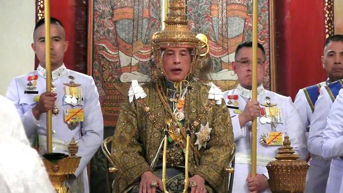 Maha Vajiralongkorn memegang kepala Ratu Suthida selama penobatan Raja baru Thailand di Istana Negara, Bangkok (4/5/2019). Dalam prosesi hadir kaum Hindu Brahma. Mereka menjadi saksi transformasi Maha Vajiralongkorn, Rama X, dari manusia menjadi sosok dewa. (Photo by Thai TV Pool /Thai Tv Pool/AFP)