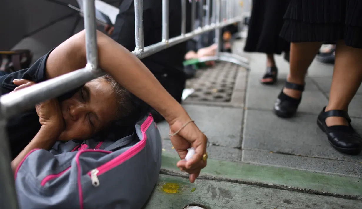 Seorang wanita tidur saat menunggu pemakaman mendiang Raja Thailand Bhumibol Adulyadej di Bangkok (25/10). Upacara akan digelar di kompleks krematorium Sanam Luang, yang berada dekat dengan Grand Palace, Bangkok. (AFP Photo/Anthony Wallace)