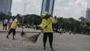 Petugas menyapu membersihkan kawasaan Monas, Jakarta, Senin (1/1). Sebelumnya, kawasan Monas menjadi titik berkumpul warga saat perayaan malam pergantian tahun dan menyisahkan sampah dari pengunjung monas. (Liputan6.com/Faizal Fanani)