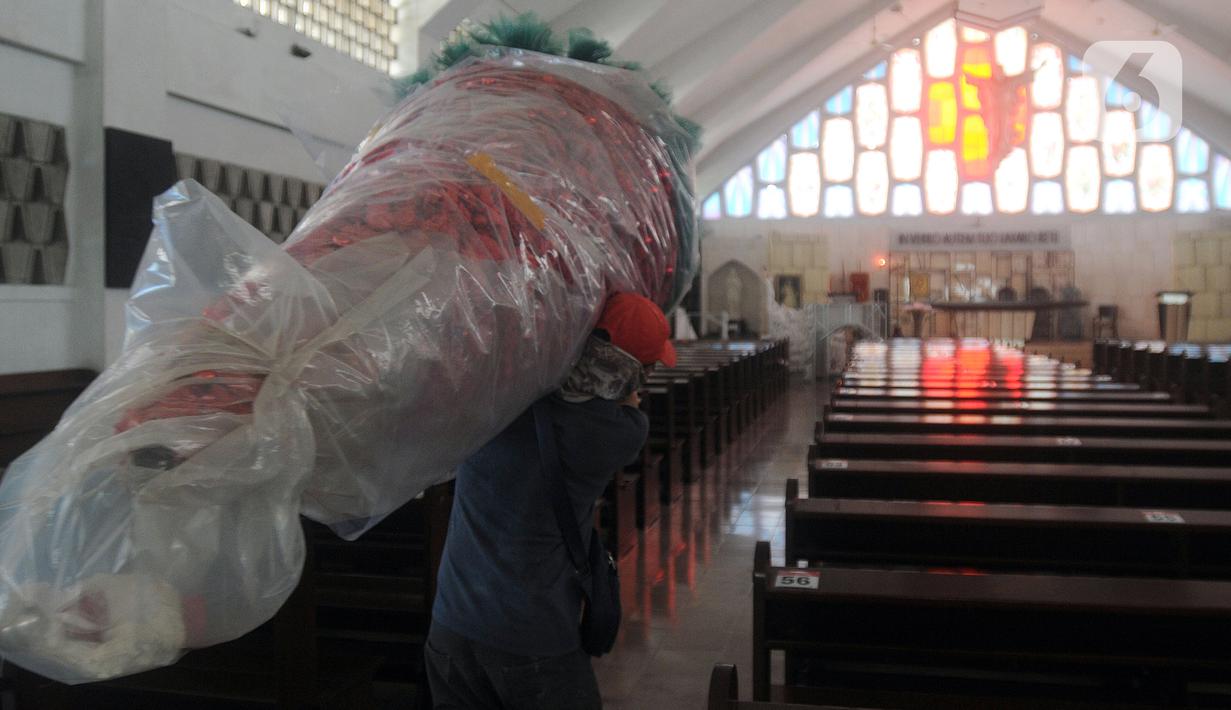 Umat Katolik membawa pohon yang akan dijadikan ornamen dekorasi Natal di Gereja Santo Barnabas, Tangerang Selatan, Banten, Kamis (23/12/2021). Sejumlah gereja di Indonesia mulai melakukan persiapan dan pemasangan dekorasi untuk menyambut misa dan perayaan Natal 2021. (merdeka.com/Arie Basuki)