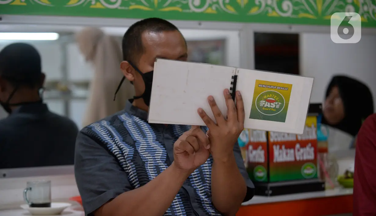Pengunjung tuna netra memilih menu makanan menggunakan panduan buku braille di Warteg FAST, Graha Raya Bintaro, Tangerang Selatan, Banten, Kamis (3/12/2020). (merdeka.com/Dwi Narwoko)