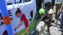 Seorang anak laki-laki membawa bola memasuki sebuah van, yang diluncurkan oleh Polisi Delhi bekerja sama dengan laboratorium Star Imaging and Path, untuk memberikan sampel usap untuk menguji virus corona Covid-19 di New Delhi, India (1/7/2021).  (AFP/Prakash Singh)
