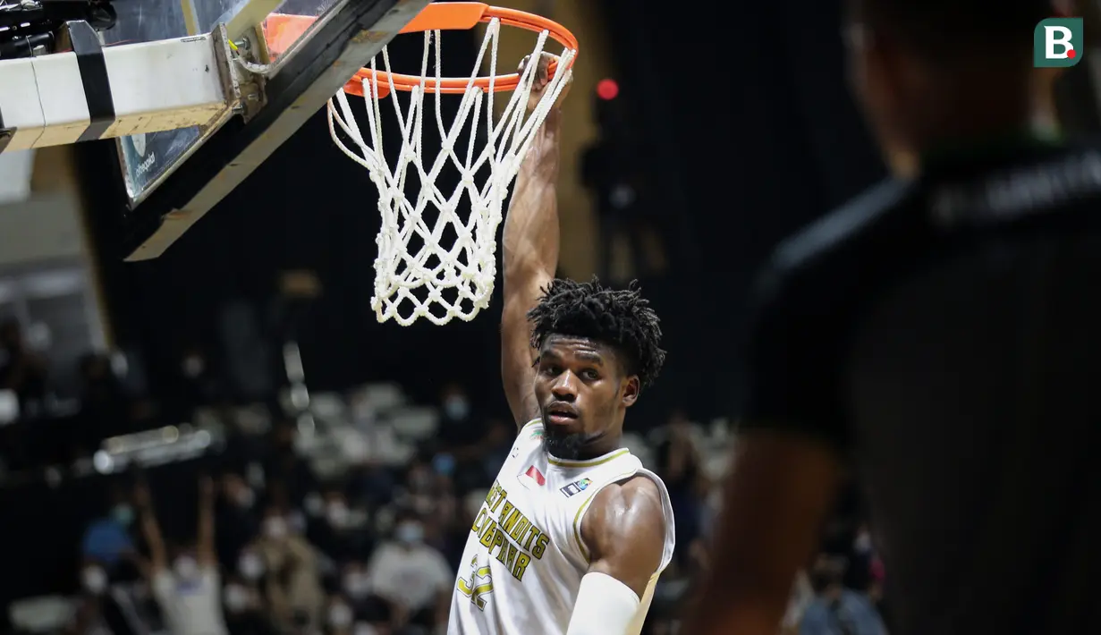 Pemain West Bandits Combiphar Solo, D. Harris bergantung di ring usai mencetak poin saat laga pekan pertama IBL Tokopedia 2022 melawan Rans PIK Basketball di Hall Basket Gelora Bung Karno, Senayan, Sabtu (15/01/2022). (Bola.com/Bagaskara Lazuardi)