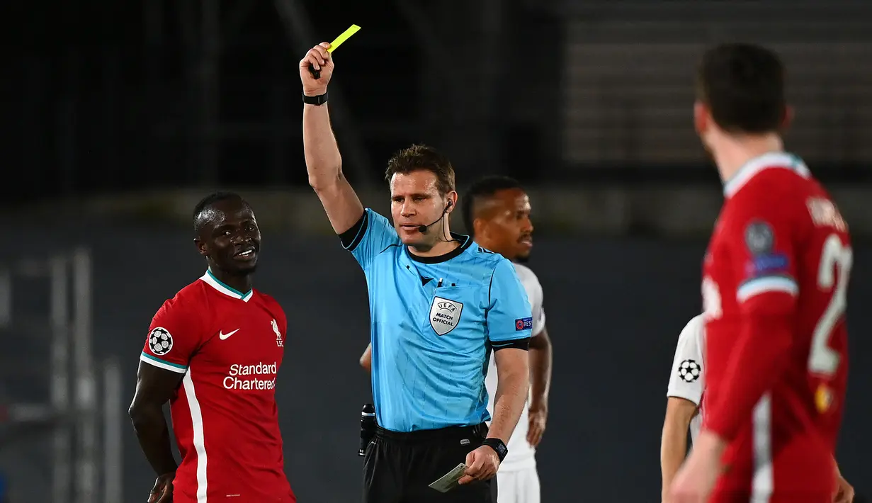 Wasit Felix Brych memberi kartu kuning kepada striker Liverpool, Sadio Mane (kiri) saat melawan Real Madrid dalam laga leg pertama babak perempatfinal Liga Champions 2020/2021 di Alfredo di Stefano Stadium, Selasa (6/4/2021). Liverpool kalah 1-3 dari Real Madrid. (AFP/Gabriel Bouys)