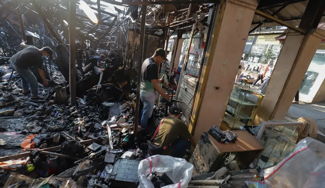 Sejumlah pedagang mengais puing dan sisa peralatan dagangan nan gosong terbakar di Pasar Taman Puring, Jakarta Selatan, Selasa (29/7/2025). (merdeka.com/Arie Basuki)