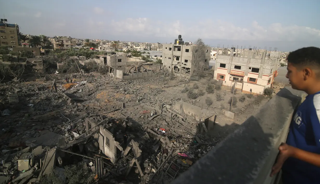 <p>Seorang anak melihat gedung-gedung yang hancur akibat bombardir Israel di Rafah, Jalur Gaza, Palestina, Minggu (22/10/2023). (AP Photo/Hatem Ali)</p>