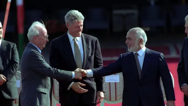 PM Israel Yitzhak Rabin (kiri) bersalaman dengan Raja Hussein dari Yordania (kanan) usai menyepakati perdamaian kedua negara, dimediasi oleh Presiden AS Bill Clinton (tengah) pada 26 Oktober 2020 (Government Press Office Israel)