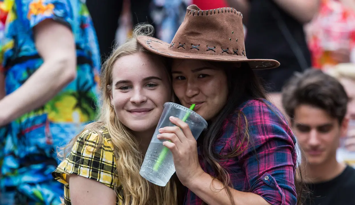 Dua fans tersenyum saat menyaksikan hari pertama turnamen rugby sevens Hong Kong, China (6/4). Para wanita ini hadir mengenakan pakaian dan atribut unik demi mendukung tim kesayangannya. (AFP Photo/Isaac Lawrence)