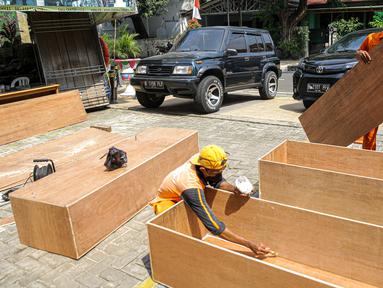 Petugas PPSU menyelesaikan pembuatan peti jenazah di Kantor Kelurahan Kayu Putih, Jakarta, Selasa, (6/7/2021). Kelurahan Kayu Putih berinisiatif membuat peti jenazah dilatar belakangi warganya yang terkendala ketersediaan peti saat angka kematian COVID-19 meningkat. (Liputan6.com/Faizal Fanani)