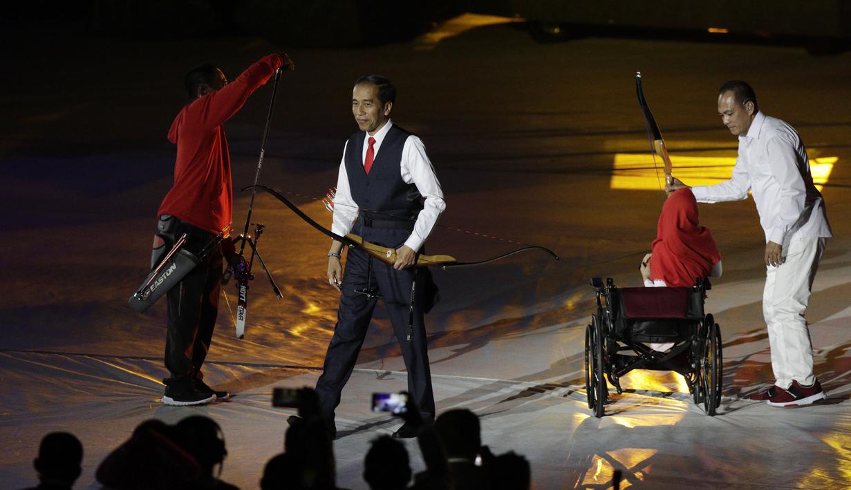 Presiden Indonesia, Joko Widodo, bersama penyandang disabilitas memanah tugu saat pembukaan Asian Para Games di SUGBK, Jakarta, Sabtu (06/10/2018). Acara tersebut dimeriahkan dengan aksi para penyandang disabilitas. (Bola.com/M Iqbal Ichsan)