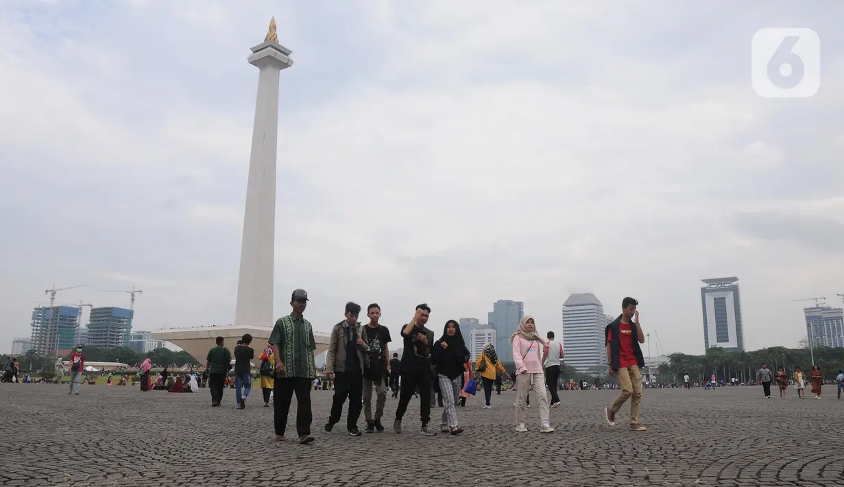 Warga berjalan-jalan di kawasan Monumen Nasional, Jakarta, Rabu (25/12/2019). Libur perayaan Natal 2019 dimanfaatkan warga Jakarta dan sekitarnya berwisata di Monumen Nasional. (Liputan6.com/Helmi Fithriansyah)