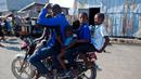 Pengendara motor membawa lima penumpang melewati area Cite Soleil di Port-au-Prince, Haiti (17/3). Daerah ini umumnya dianggap sebagai salah satu daerah termiskin dan paling berbahaya di Belahan Barat. (AP Photo/Dieu Nalio Chery)