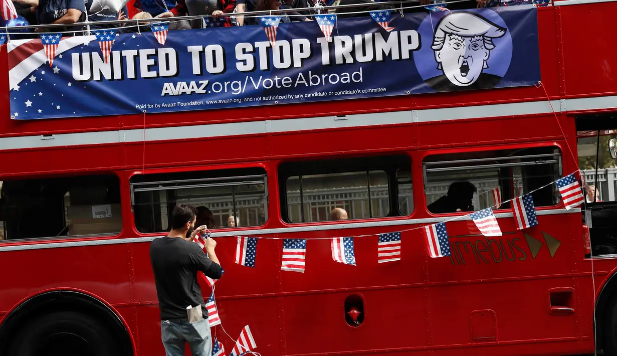 Seorang pria memasang bendera AS mini di bus kampanye menolak Trump di London, Inggris, Rabu (21/9). Mereka mengajak warga AS yang berada di luar negeri untuk tidak memilih Trump sebagai Presiden AS. (REUTERS / Stefan Wermuth)