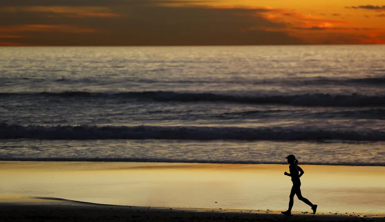 Seorang wanita saat berlari dipantai setelah matahari terbenam di Cardiff, California (27/1/2016). Wilayah Selatan California ini usai di landa Badai El Nino. (REUTERS/Mike Blake)