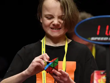 Seorang anak semangat memecahkan permainan rubik pada kejuaraan kubus Rubik Dunia di Melbourne, Australia (12/7/2019). Kejuaraan Dunia diadakan setiap dua tahun dan telah menarik 905 pesaing dari seluruh dunia yang bersaing dalam 18 acara yang berbeda. (AFP Photo/William West)