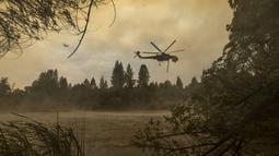Helikopter Billings 4AJ mengisi ulang air untuk dijatuhkan ke Oak Fire dekat Mariposa, California, Amerika Serikat, 26 Juli 2022. Lebih dari seperempat kobaran api dekat Taman Nasional Yosemite telah berhasil dipadamkan. (DAVID MCNEW/AFP)