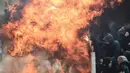 Suporter Ajax Amsterdam mencoba untuk melindungi diri dari ledakan bom molotov selama bentrokan dengan polisi anti huru-hara Yunani sebelum pertandingan Liga Champions melawan AEK Athena di Stadion Olimpiade Athena, Selasa (27/11). (Aris Messinis/AFP)