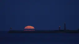 Bulan purnama yang dikenal sebagai Harvest moon terbit di atas pelabuhan Whitby, di Whitby, Inggris, Senin (20/9/2021). Bulan purnama Harvest Moon biasanya terjadi di bulan September, namun kadang juga terlambat hingga ke Oktober. (AP Photo/Alastair Grant)