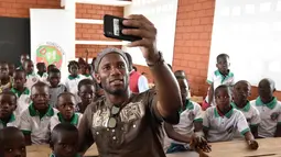 Mantan penyerang Chelsea, Didier Drogba berswafoto dengan murid-murid selama peresmian sekolah yang disponsori dirinya di Pokou-Kouamekro, dekat Gagnoa, Pantai Gading tengah barat (17/1). (AFP Photo/Sia Kambou)