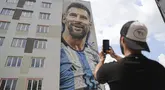Seniman jalanan Argentina Maximiliano Bagnasco mengambil foto mural yang menggambarkan superstar sepak bola Argentina Lionel Messi, yang ia lukis, di Tirana, Albania, pada Kamis (8/6/2023). (AP Photo/Llazar Semini)