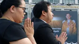 Sejumlah warga berdoa di dekat Grand Palace di Bangkok, Thailand, Rabu (19/10). Untuk menghormati Raja Bhumibol Adulyadej, Grand Palace dipasangi gambarnya. (REUTERS / Chaiwat Subprasom)