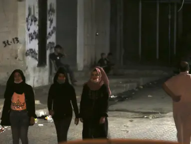 Sejumlah mengenakan masker saat berjalan ke rumah keluarga mereka selama penguncian yang diberlakukan selama pandemi virus corona, di kamp pengungsi Shati, di Kota Gaza, Selasa, (1/9/2020). (AP Photo/Adel Hana)
