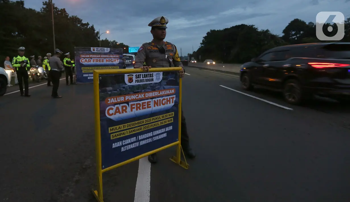 Petugas dari Polres Bogor memasang rambu penutupan jalan di pintu keluar Tol Gadog, Bogor, Sabtu (31/12/2022). Penutupan jalan jalur Puncak Bogor untuk gelaran Car Free Night dimulai sejak pukul 18.00 WIBdan dibuka kembali esok pagi pukul 06.00 WIB. (merdeka.com/Arie Basuki)