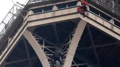 Petugas pemadam kebakaran berusaha mendekati seorang pria (baju hitam di bawah) yang memanjat Menara Eiffel tanpa peralatan keselamatan di Paris, Senin (20/5/2019). Akibat ulahnya, Menara Eiffel ditutup dan pihak pengelola melakukan evakuasi dan pengamanan. (AP/Michel Euler)