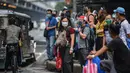 Orang-orang yang memakai masker menunggu transportasi di sebuah jalan di Manila, sehari sebelum pihak berwenang mencabut perintah tinggal di rumah pada Selasa (7/9/2021). Filipina akan mencabut lockdown di ibu kota Manila pada Rabu (8/9), saat kasus corona harian naik dua kali lipat (Ted ALJIBE/AFP)