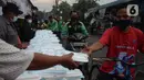 Warga menerima pembagian nasi bungkus gratis di Posko Perjuangan Rakyat (POSPERA), Jakarta, Rabu (10/3/2021). Pembagian 500 nasi bungkus beserta masker dan vitamin secara gratis setiap harinya dalam bentuk meringankan beban warga di tengah pandemi Covid-19. (merdeka.com/Imam Buhori)