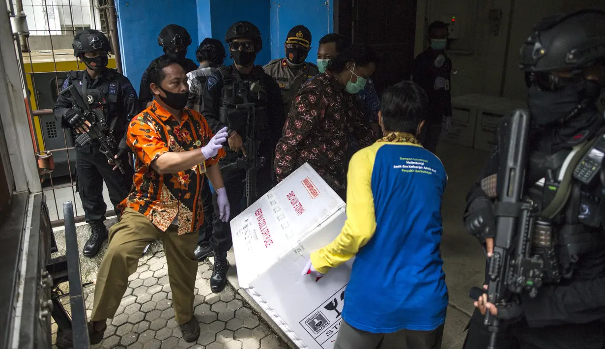 Pekerja menurunkan vaksin COVID-19 produksi Sinovac dari truk pengawalan polisi di Surabaya pada Senin (4/1/2021).  Pemerintah mulai mendistribusikan 3 juta dosis vaksin Covid-19 asal perusahaan China, Sinovac, ke 34 provinsi Indonesia. (Photo by Juni Kriswanto / AFP)