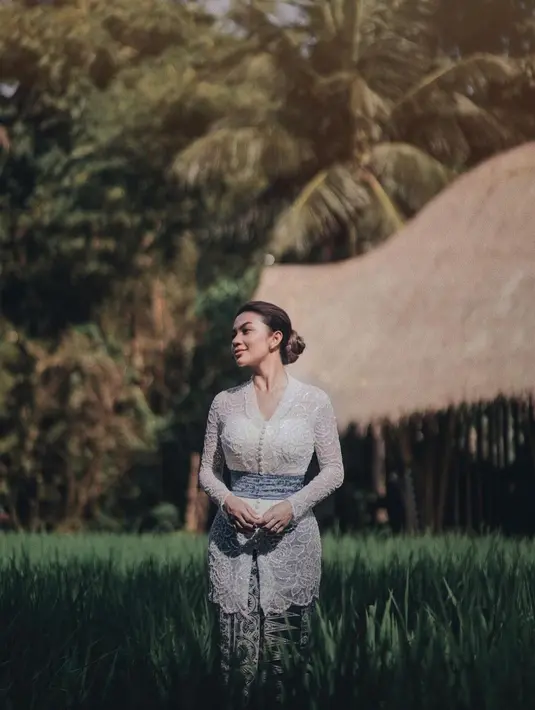 Cantiknya penampilan Ariel Tatum dibalut kebaya putih yang sederhana. Penampilannya bak gadis Bali, dilengkapi dengan kain batik sebagai rok dan selendang biru yang diikatkan di pinggangnya. [Foto: Instagram/arieltatum]