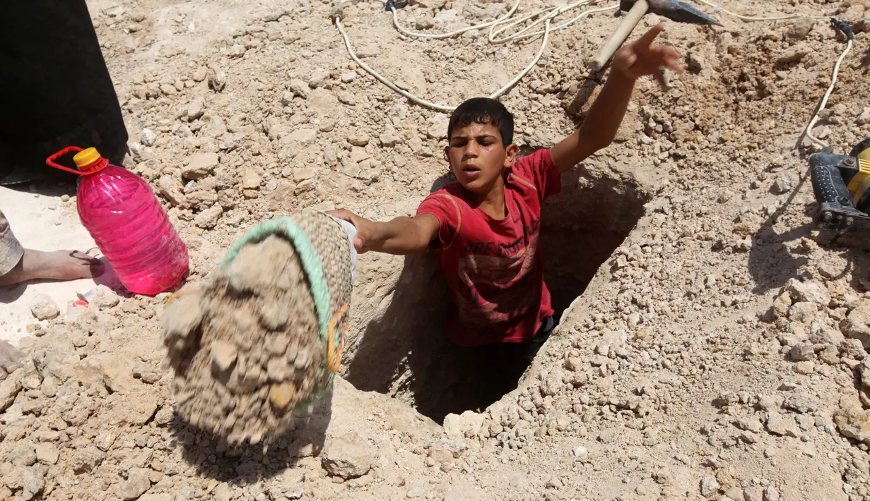 Seorang anak laki-laki menggali kuburan di pemakaman Wadi al-Salam, di Najaf, selatan Baghdad, Irak. 27 Juli 2016. Sejumlah kuburan banyak yang rusak akibat perang yang terjadi di Irak. (REUTERS/Alaa Al-Marjani)