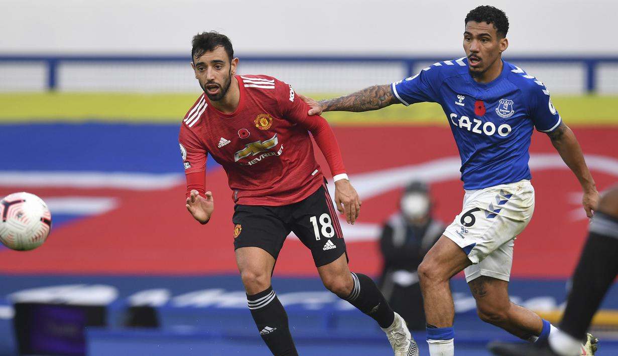 Gelandang Manchester United, Bruno Fernandes, berebut bola dengan gelandang Everton, Allan, pada laga lanjutan Liga Inggris di Goodison Park Stadium, Sabtu (7/11/2020) malam WIB. Manchester United menang 3-1 atas Everton. (Paul Ellis/Pool via AP)