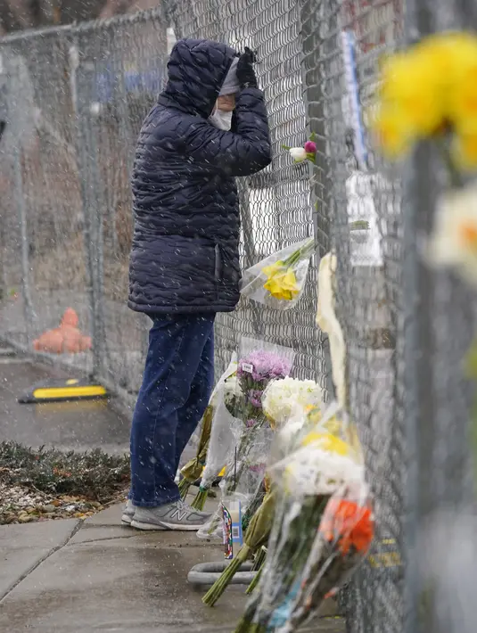 Seorang pelayat bersandar di pagar yang dipasang di sekitar tempat parkir tempat penembakan massal terjadi di toko kelontong King Soopers di Boulder, Colorado (23/3/2021). (AP Photo/David Zalubowski)