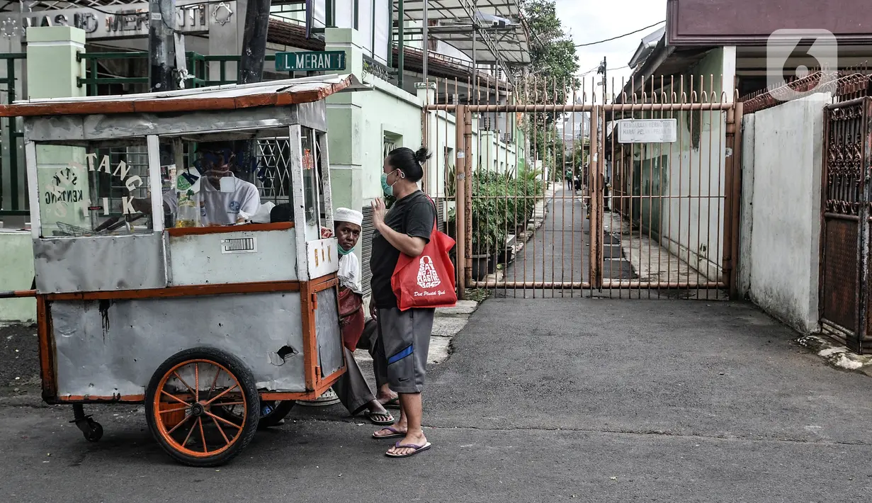 Warga membeli jajanan kaki lima di depan akses ke permukiman yang ditutup di kawasan Bungur, Jakarta, Rabu (10/2/2021). Data yang tercatat di laman corona.jakarta.go.id menyebut zona merah di Jakarta Selatan sebanyak 41 RW dan Jakarta Pusat 16 RW. (merdeka.com/Iqbal S. Nugroho)