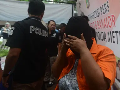 Seorang tersangka menutupi wajahnya saat dihadirkan polisi dalam rilis kasus praktik prositusi di Apartemen Kalibata City, Jakarta, Kamis (29/3). Polisi mengamankan empat tersangka, SL, IP, MP dan YP bersama barang bukti. (Merdeka.com/Imam Buhori)