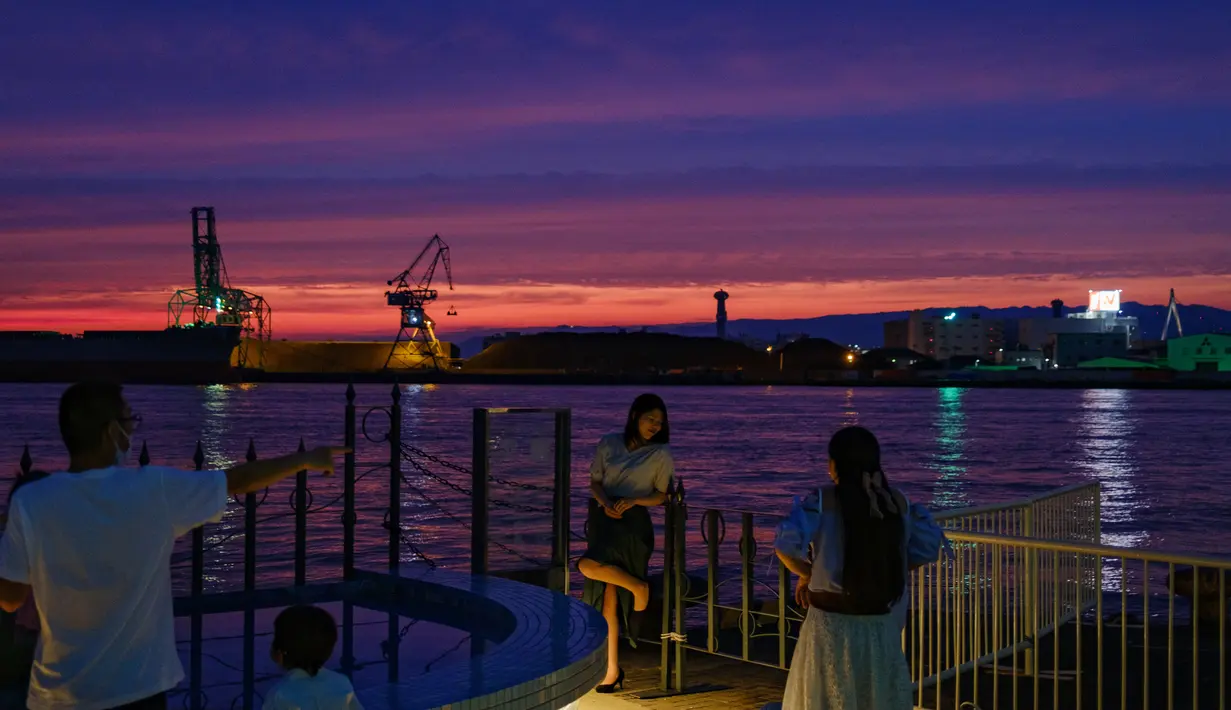 Seorang wanita berpose untuk foto di kawasan pejalan kaki pelabuhan di Osaka (20/9/2020). Pelabuhan Osaka juga memiliki mitra kembar dengan Pelabuhan Busan. (AFP/Philip Fong)