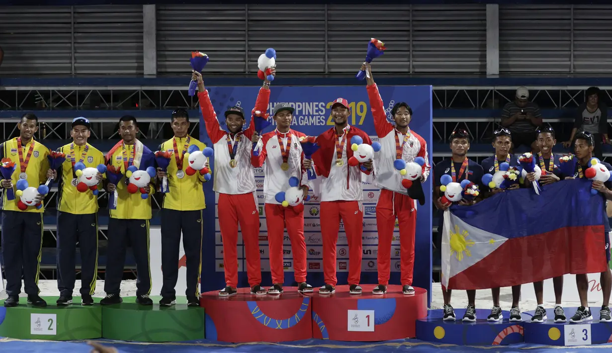 Tim voli pantai Indonesia melakukan selebrasi saat upacara pemberian medali pada voli pantai beregu putra SEA Games di Subic Court Tennis, Filipina, Jumat (6/12). Indonesia berhasil meraih emas. (Bola.com/M Iqbal Ichsan)