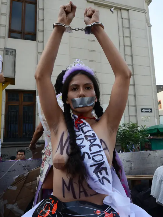 Aktivis memborgol tangan sambil bertelanjang dada saat menggelar aksi Hari Internasional untuk Penghapusan Kekerasan terhadap Perempuan di Lima, Peru, Rabu (25/11). Mereka menuntut legalisasi aborsi dalam kasus pemerkosaan. (AFP PHOTO/CRIS BOURONCLE)
