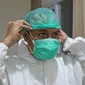 dr Rahmadi Iwan Guntoro, Sp.P memakai pelindung rambut di Rumah Sakit Haji, Jakarta, Kamis (9/4/2020). Standar APD tingkat perlindungan ketiga diperuntukkan untuk ruang prosedur dan tindakan operasi pada pasien dengan kecurigaan atau sudah terkonfirmasi COVID-19. (Liputan6.com/Herman Zakharia)