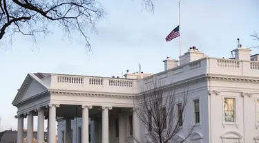 Bendera Amerika tampak berkibar setengah tiang untuk menandai 500.000 kematian akibat Covid-19 di Gedung Putih di Washington D.C. pada Senin (22/2/2021). Presiden Joe Biden memerintahkan agar bendera AS di properti federal diturunkan menjadi setengah tiang selama lima hari. (SAUL LOEB/AFP)