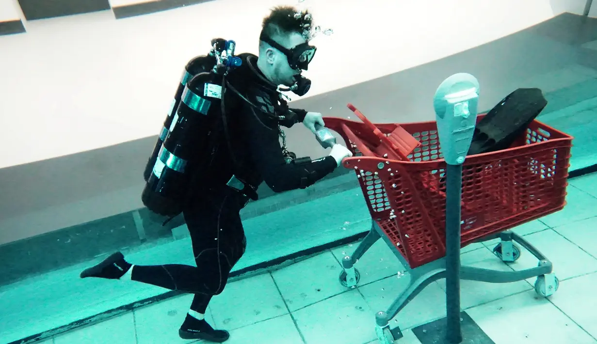 Seorang penyelam menggunakan kereta belanja tiruan saat menyelam di Deep Dive Dubai, Dubai, Uni Emirat Arab, 10 Juli 2021. Deep Dive Dubai adalah kolam renang terdalam di dunia. (GIUSEPPE CACACE/AFP)