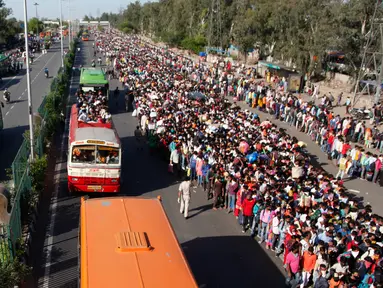 Buruh migran India menunggu bus untuk mengangkut mereka menuju kampung halaman setelah pemberlakukan lockdown di New Delhi, Sabtu (28/3/2020). Arus eksodus massal ini terjadi beberapa jam setelah otoritas setempat mengumumkan menyediakan ratusan bus bagi yang ingin meninggalkan Delhi. (AP Photo)
