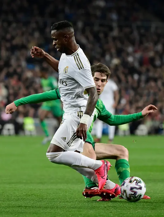 Pemain depan Real Madrid, Vinicius Junior berebut bola dengan bek Real Sociedad, Aritz Elustondo pada laga perempat final Copa del Rey di Santiago Bernabeu, Kamis (6/2/2020). Real Madrid gagal melaju ke semifinal Copa del Rey setelah dibungkam Real Sociedad dengan skor 3-4. (JAVIER SORIANO/AFP)