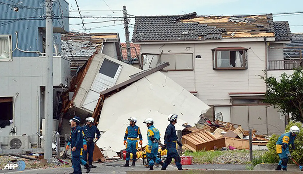 Petugas pemadam dan polisi memeriksa kondisi rumah yang rusak akibat tornado di Koshigaya, pinggiran kota Tokyo. (AFP/Yoshikazu Tsuno/wwn)