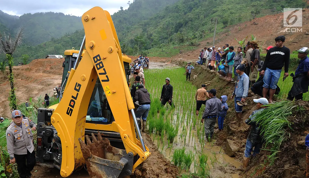 Warga memandu alat berat melalui jalan kecil menuju lokasi longsor di Dusun Cimapag, Sirnaresmi, Cisolok, Sukabumi, Jawa Barat, Selasa (1/1). Longsor menimbun 30 unit rumah. (Merdeka.com/Arie Basuki)